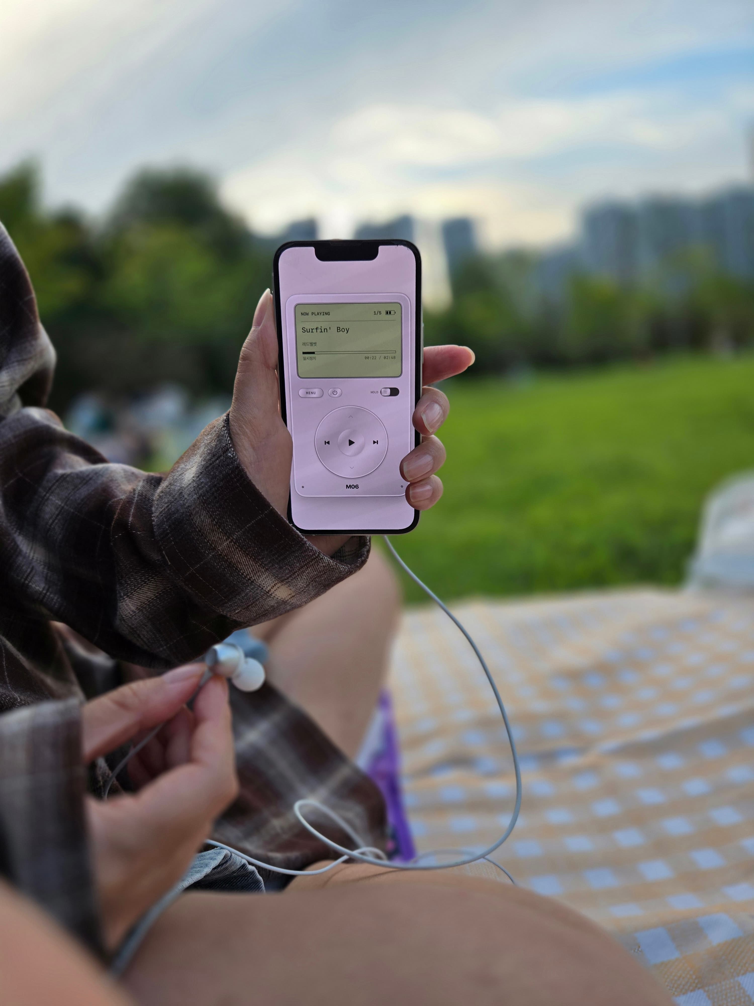 屋外で有線イヤホンと一緒にiPhoneのM06を使う様子